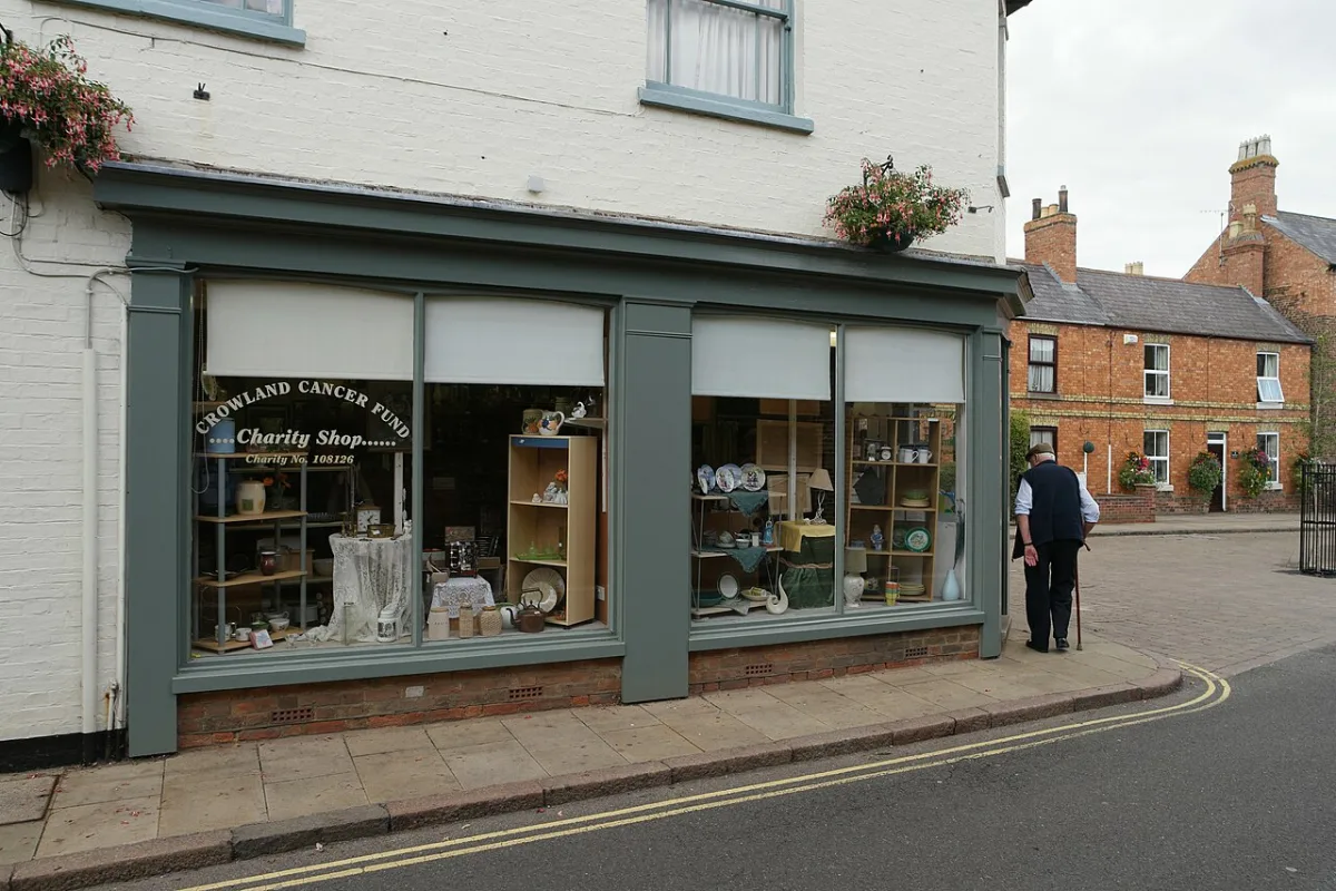 Etalage van een charity shop met tweedehands serviesgoed en decoratieve items